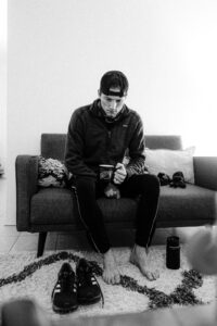 Barefoot man on couch with coffee mug and running gear at his feet