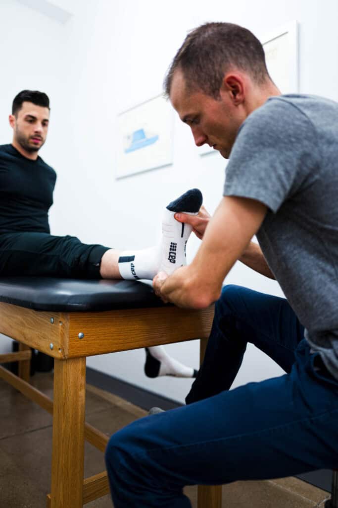 Physical therapist performing foot and ankle assessment on athlete lying on table