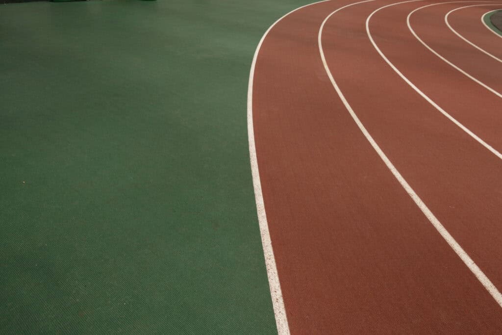 Curved section of indoor track with green outer lane and brown inner lanes